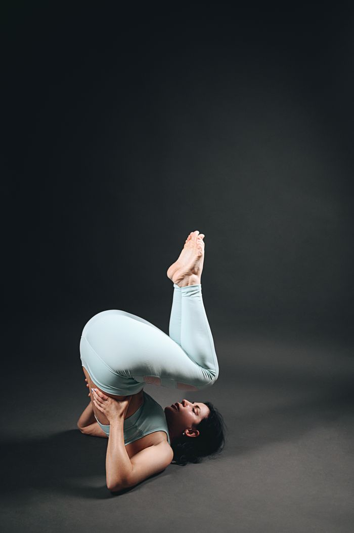 about-04 Woman performing challenging yoga pose showing strength and flexibility in an indoor studio setup.